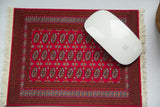Bokhara MouseRug in red with elephant footprint design, partially covered by a white mouse.
