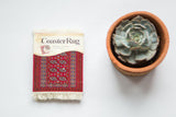 Bokhara CoasterRug with saturated red field, elephant footprint and stylized floral borders.