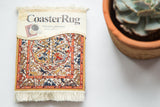 Persian Oriental Rug Coaster packaging, with label, white fringe, and intricate Soumac design.