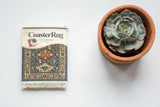 Caucasian Kuba CoasterRug with a geometric pattern in denim blue, rust red, and ivory.