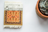 Red and gold floral Mughal Lotus CoasterRug with fringe and Metropolitan Museum of Art band.