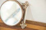 Bottom fleur de lis mounting bracket detail of the vintage shaving mirror with patina.