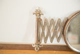 Fleur de lis mounting bracket and rusted accordion arm of vintage shaving mirror.