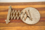 Rusty metal accordion arm and fleur de lis bracket of vintage shaving mirror.