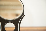 Vintage Hollywood Mirror's black Art Deco frame with white stripe and circular detail.