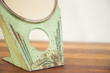 Mint green Art Deco mirror base with chippy paint and dark green geometric pattern.