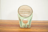 Chipped mint green base of an Art Deco Hollywood mirror with dark green stripes.