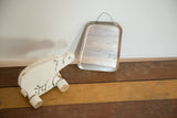 Antique small beveled glass mirror with irregular bell shape and wire hanger.