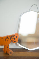 Art Deco bell mirror's curved top edge, hanging wire, and light spotted patina.