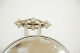 Ornate, aged metal hardware and beveled glass edge of the Victorian barber mirror.
