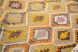 Vibrant geometric patterns in yellow, orange, lavender, and brown on a vintage Kilim.