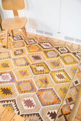 Mosaic of yellow, orange, brown, and lavender geometric patterns on the vintage Kilim rug.