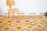 Flat-woven vintage Kilim rug displays geometric yellow, orange, brown, and lavender diamond patterns.