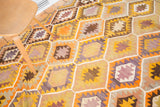 Hand-woven texture and vibrant yellow, orange, and lavender geometric pattern on vintage Kilim rug.