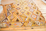 Vintage Yellow and Orange Kilim rug with geometric border, fringe, and lavender accents.
