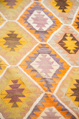 Playful geometric flatweave pattern of vintage Kilim rug in yellow, orange, lavender, and brown.