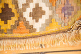 Vintage Kilim rug detail showing flatweave geometric pattern in yellow, orange, and lavender with fringe.