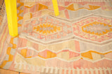 Vintage Kilim rug section featuring faded pink, yellow, and grey geometric patterns.