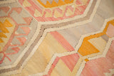 Vintage Kilim flatweave rug with faded pink, yellow, and grey geometric pattern.