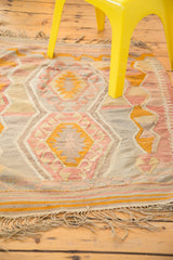 Vintage faded pink, yellow, and grey Kilim rug with geometric pattern, 3'6