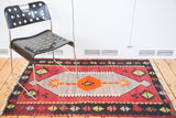 Vintage Kilim rug with prominent geometric motifs in lavender, orange, and cranberry.