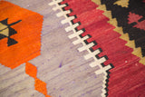Stepped geometric patterns in lavender, cranberry red, orange, and black on a Kilim.