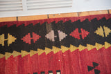 Vintage Kilim rug's serrated geometric pattern in black, cranberry, and lavender tones.