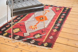 Vintage Kilim rug with cranberry red field, black geometric border, and white fringe.