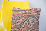 Antique Kerman rug fragment pillow displaying traditional floral patterns in muted red and blue.