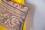 Corner detail of vintage Persian Kerman rug pillow with faded patterns and textured surface.
