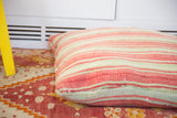 Faded red and pale green striped pattern on a handwoven Moroccan Kilim pillow.