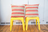Pair of large striped Kilim pillows, displaying faded pink and green woven patterns.