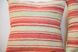 Hand-woven Kilim pillow texture in faded pink and pale green stripes.