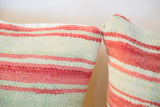 Hand-woven Kilim pillow with faded pink and light green striped texture.