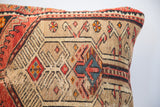 Intricate geometric pattern with camel, red, and blue accents on a vintage rug pillow.