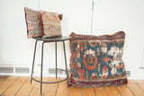 Antique Lilihan floor pillow: dark blue, orange-red, green geometric Persian rug fragment, aged wear.