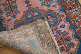 Folded Malayer runner displaying blush rose field, blue tribal plant motifs, tattered edge.