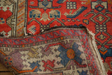 Folded vintage Malayer rug edge revealing intricate hand-knotted foundation and worn cherry red pile.