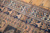 Distressed geometric patterns in navy blue, faded peach, and aqua on the antique Afshar rug.