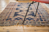 Allover distressed navy, peach, and ivory geometric patterns on an antique Afshar rug with fringed ends.