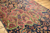 Intricate rose-pink and deep navy floral pattern with celadon green vines on a Farahan Sarouk.