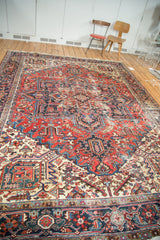 Ivory spandrel with rectilinear patterns and distressed navy border details on a Heriz rug.