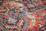 Distressed vintage Heriz rug texture with navy, red, and blue rectilinear patterns.
