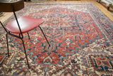 Distressed vintage Heriz carpet with rectilinear motifs in deep red, indigo, and ivory.