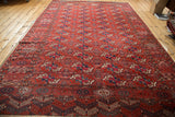 Tekke Bokhara rug's intricate alternating geometric border, madder root red field, green and navy gul motifs.