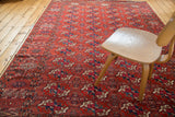 Repeating Tekke Bokhara gul motifs on a rich madder red field with varied green, navy, and ivory fills.