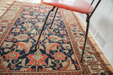 Distressed navy field featuring coral and beige herati patterns on an antique Malayer rug.