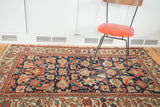 Distressed coral and blue herati mahi-mahi design on antique Malayer rug's navy field.