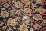 Antique Malayer rug detail, featuring distressed navy field, orange mahi-mahi motifs, and visible foundation.
