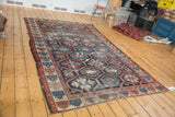 Distressed vintage Bakhtiari rug with geometric lattice design and red, blue dragon border.